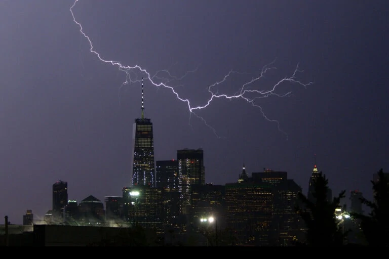 Lightning striking over city skyline at night.