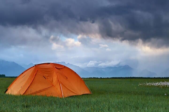 Acampamento durante uma tempestade com montanhas em primeiro plano