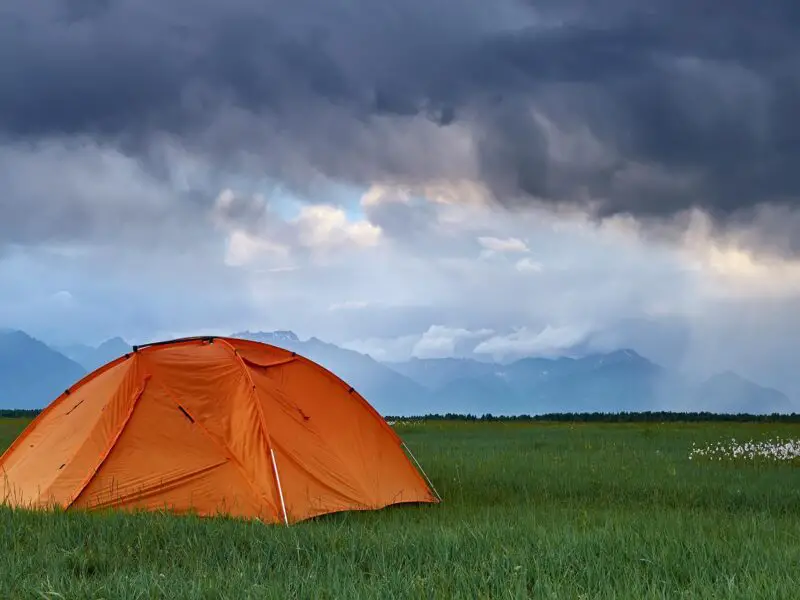 Camp during a thunderstorm with mountains on foreground