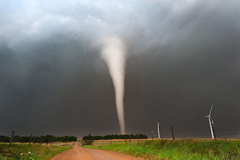 Tornado formándose sobre un paisaje rural con turbinas eólicas.
