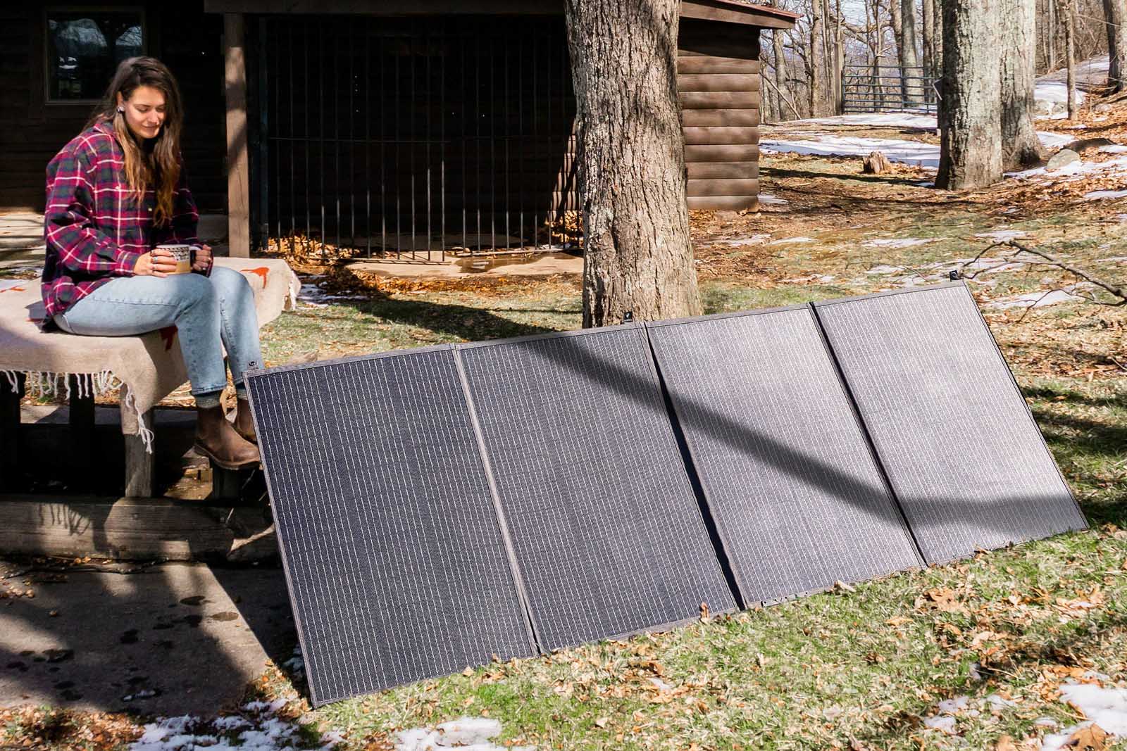 Femme avec des panneaux solaires portables dans une forêt enneigée.