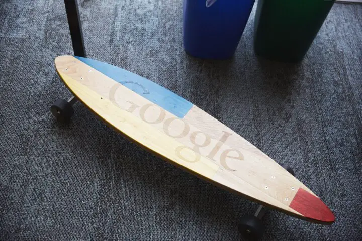 Google-branded skateboard on carpeted floor.